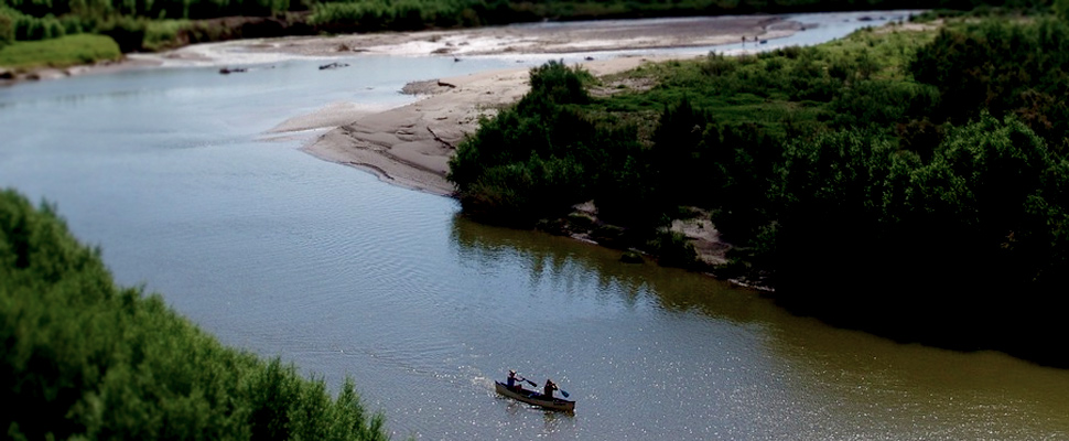 Canoe with two people sailing on the Rio Grande between the southern United States and northern Mexico