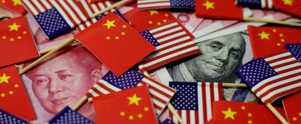 US dollar bill and a Chinese yuan bill are seen between the United States and China flags