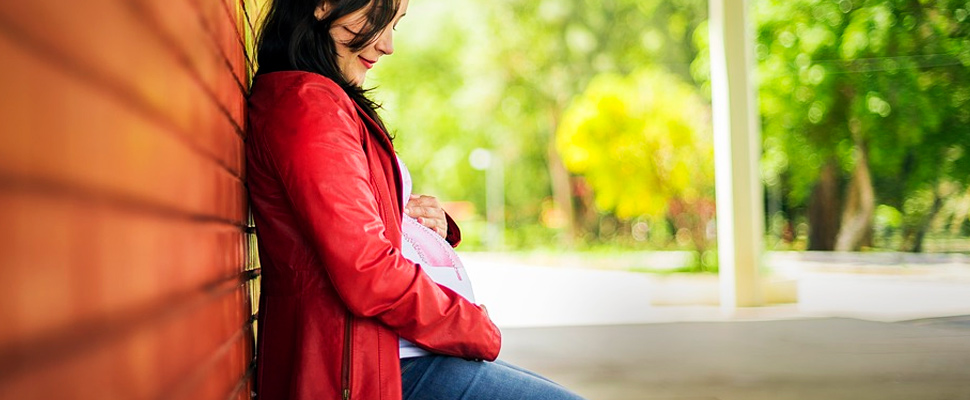 Pregnant woman sitting on a street.