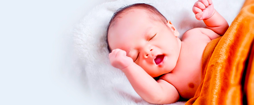 Baby lying sleeping with brown blanket.