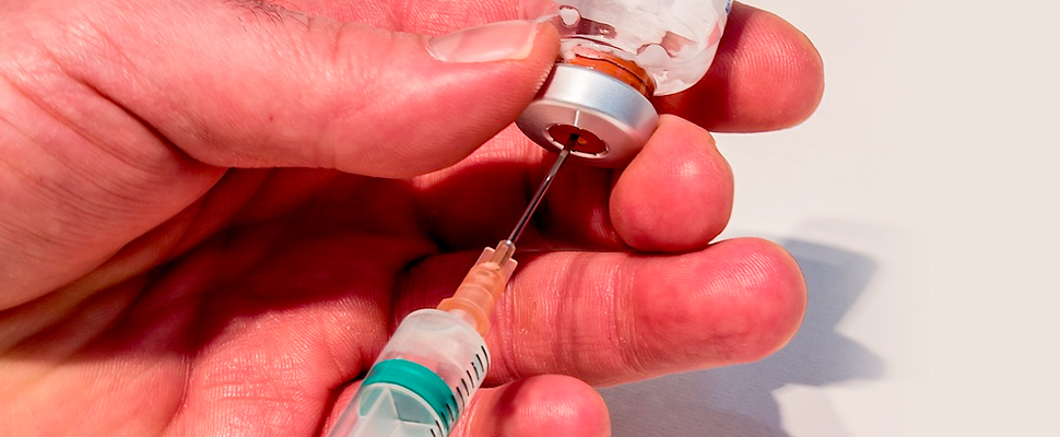 Person filling a syringe with medication.