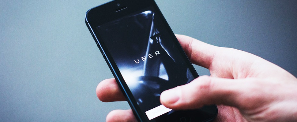 Person holding a cell phone where the Uber application logo is seen