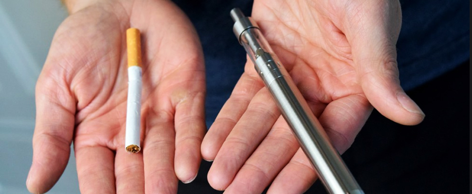 Person holding in his hands a normal and an electronic cigarette.