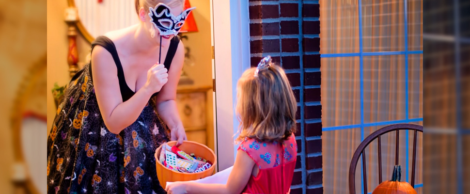 Woman delivering candy to a girl on Halloween.