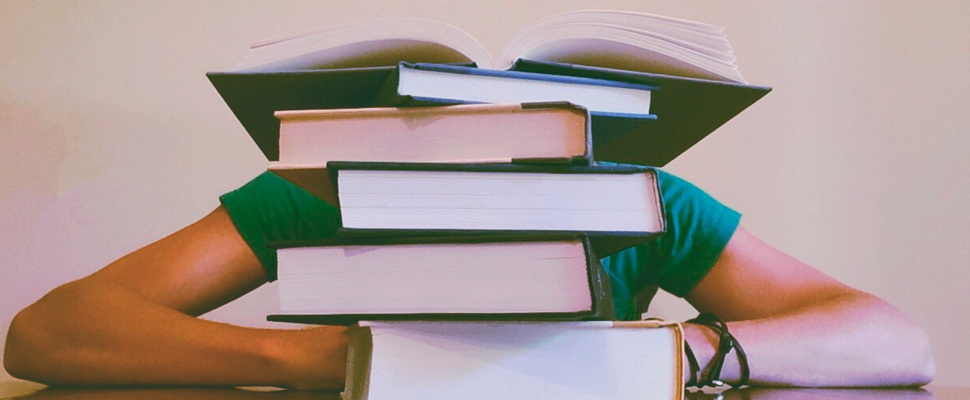 Young man lying behind study books.