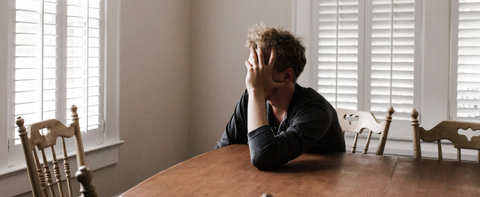 Man leaning on wooden table.