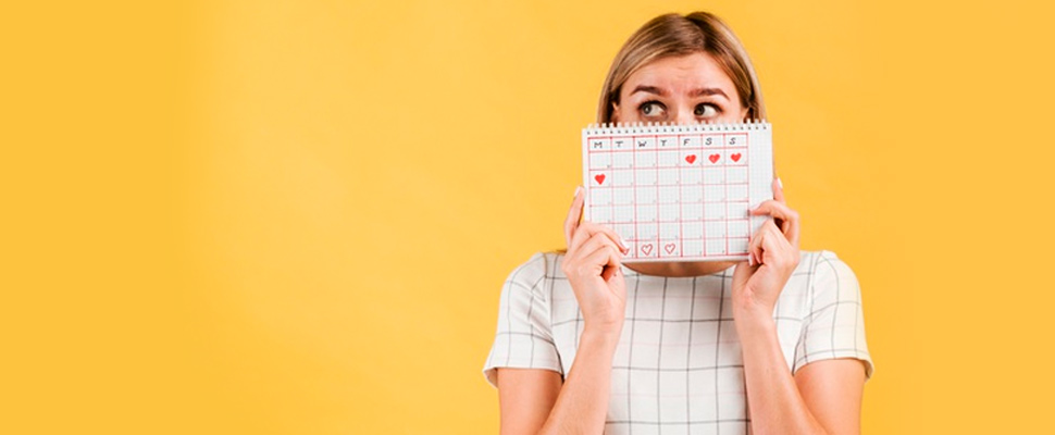 Woman holding a calendar with marked menstrual cycle days.