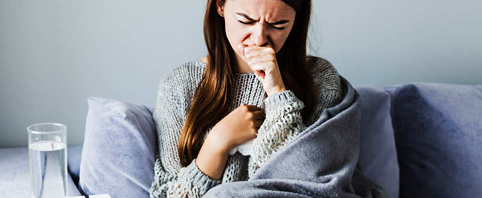 Woman under a blanket coughing.