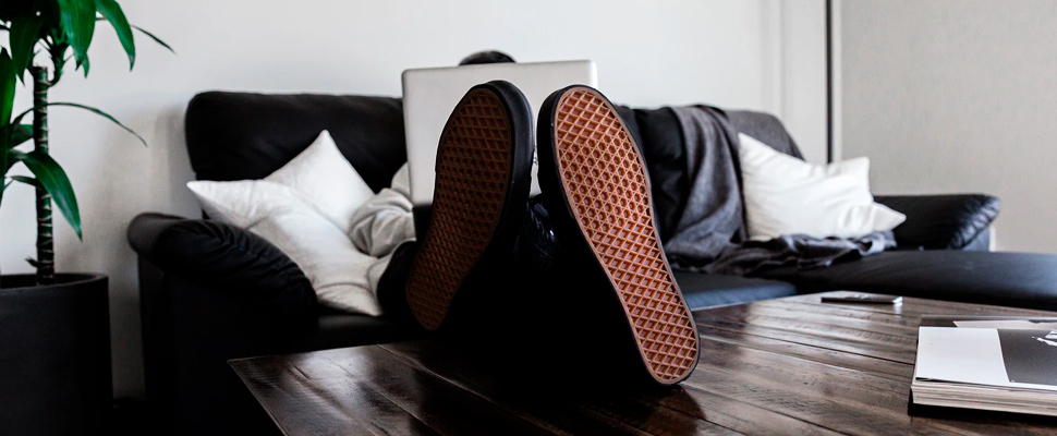 Person lying on a sofa using a computer.