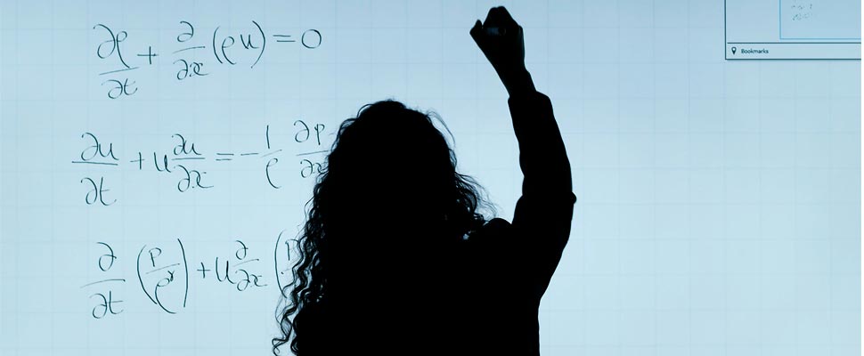 Woman writing equations on a board.