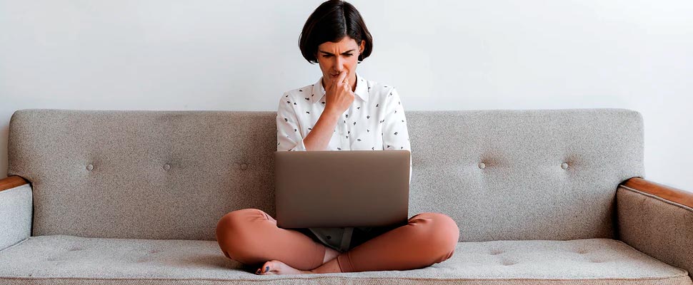 Woman checking her computer on a sofa.