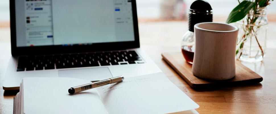 Laptop and note pad with a cup.