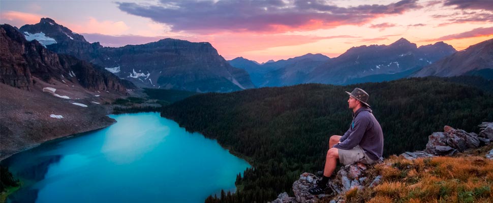 Man sitting on a mountain sitting on a rock.