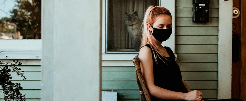 A girl in a mask sitting on her porch during the coronavirus shutdown.