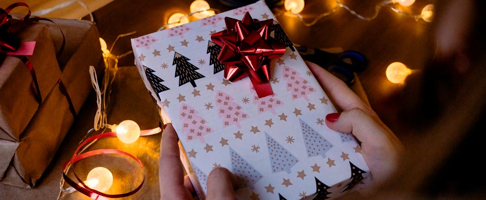 Person wrapping a gift box with ribbon