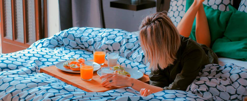 Woman having breakfast lying on a bed