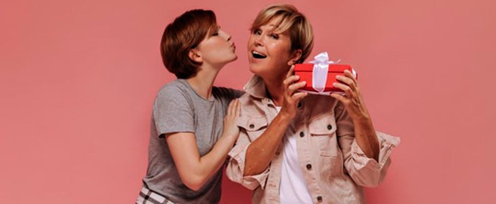 Daughter hugging her mother who is holding a gift