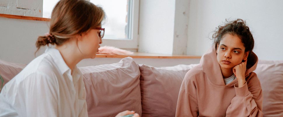 Two women sitting on a couch in the middle of a therapy