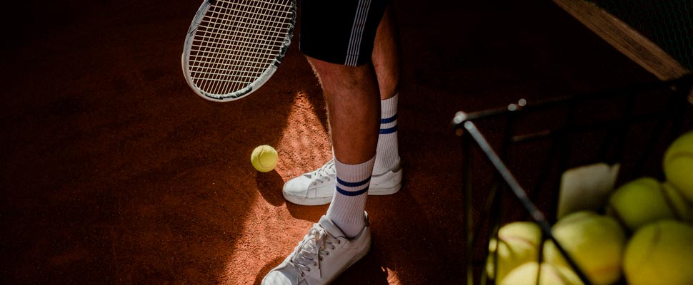 Legs of man with a racket and baseballs