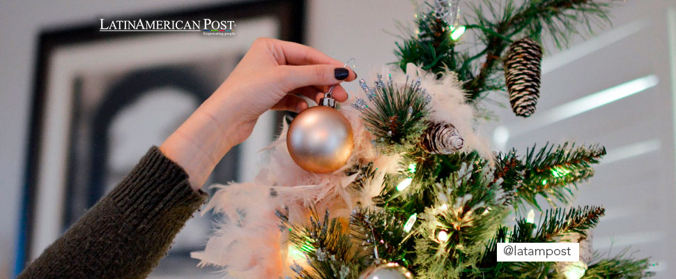 Person holding an arrangement near Christmas tree