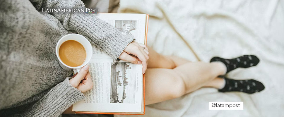 Woman holding a cup of coffee and a book