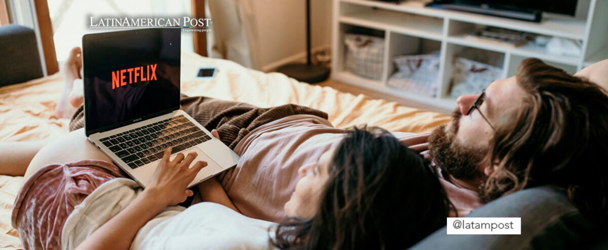 Couple lying on a bed watching Netflix on a computer