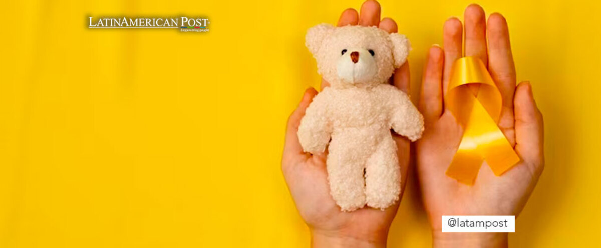 Hand with a stuffed animal and a ribbon of the fight against cancer