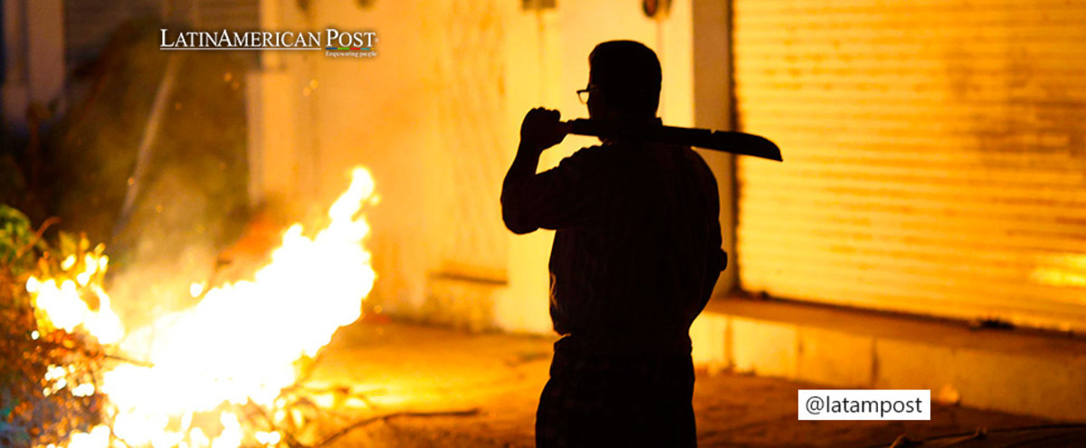 A man stands guard outside his house