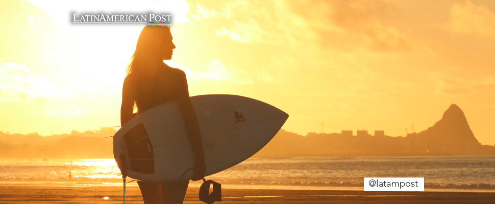 Woman holding a surfboard standing on shoreline