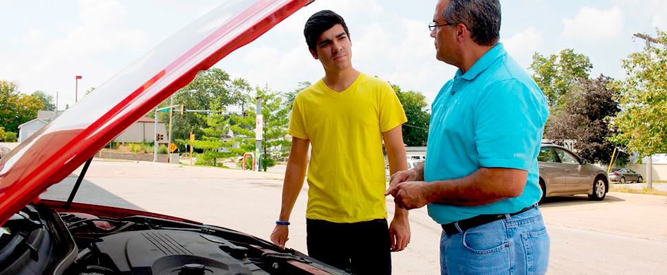 Two people checking the engine of a car